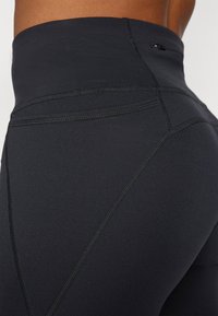 Magas derekú fekete leggings sima, rugalmas anyagból, lapos varrásokkal és kontúros kialakítással az optimális illeszkedés és kényelem érdekében.