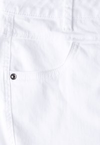 Witte denim stof met een klassiek zakontwerp en een zilveren knoop. De textuur is glad en de stiksels zijn zichtbaar langs de randen.