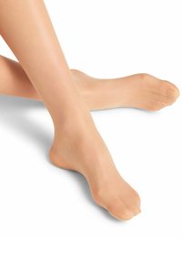 Collant trasparenti nudi indossati ai piedi, che mettono in evidenza la texture liscia e il design senza cuciture, con punte rinforzate e una finitura leggermente lucida.