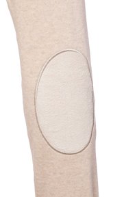 Beige legging met een soepele, gebreide textuur, met lichte stofpatches op de knieën voor versterking en extra duurzaamheid.