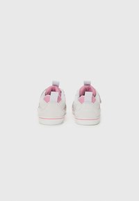 Lys grå sneakers med rosa detaljer, laget av semsket skinn, gummisåle og løftelapper bak for enkel påkledning.