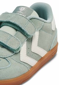 Jasnoniebieski zamszowy tenisówka z białymi akcentami i paskami na rzep. Posiada fakturowaną powierzchnię i gumową, naturalnego koloru podeszwę.