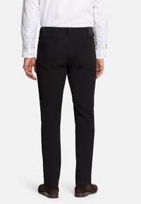 Black trousers with a straight cut, featuring two back pockets, made of smooth fabric, paired with a white button-up shirt.
