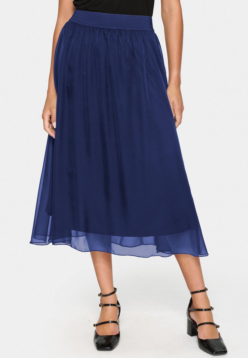 Marinblå chiffon-midi kjol med elastisk midja, med en flödande design och lagerstruktur. Utsmyckad med en genomskinlig nederkant.