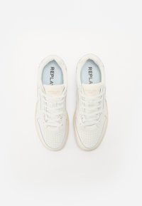 White leather sneakers with perforated toe, light blue lining, reinforced tongue with "REPLAY 1981" branding, and beige rubber sole.