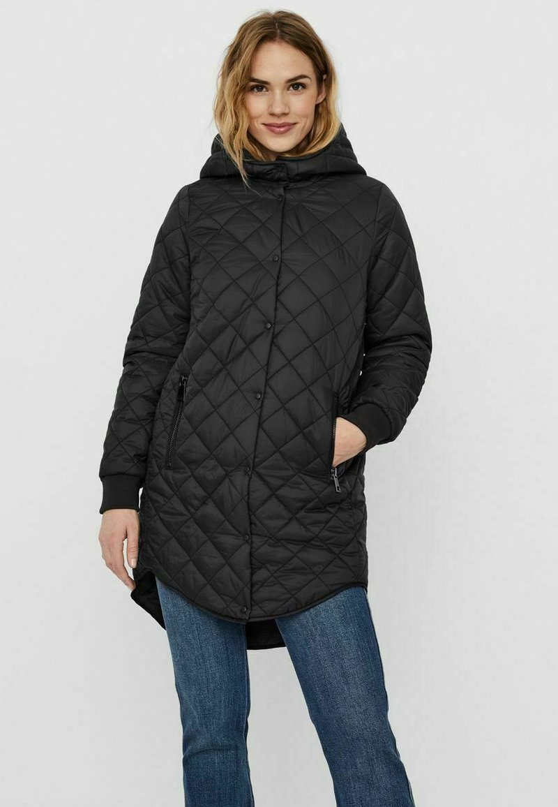 Giacca lunga nera trapuntata con cappuccio, caratterizzata da motivi a diamante, chiusura frontale con bottoni automatici e tasche laterali con zip. Materiale morbido e leggero.