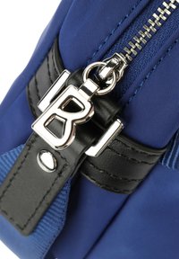 Borsa in nylon blu con manico in pelle nera, accessori in argento e chiusura a zip con un distintivo tirazip a forma di 'B'. Finitura testurizzata.