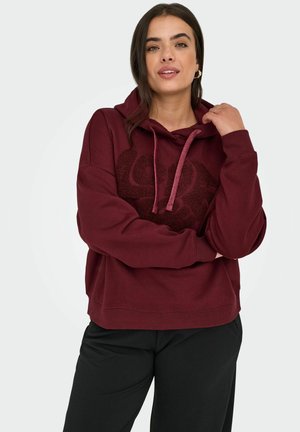 Bordový sweatshirt s designem loga na přední straně, s kapucí na šňůrky a žebrovanými manžetami a lemem. Tkanina se jeví jako měkká a mírně texturovaná.