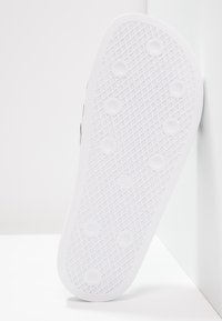 White rubber shoe sole with a textured pattern, featuring circular grips and a smooth edge. Number "6" embossed near the bottom.
