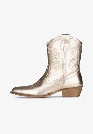 Gouden metalen cowboylaars met gegraveerd krulpatroon, ronde neus, lage blokhak en decoratieve stiksels langs de naden.