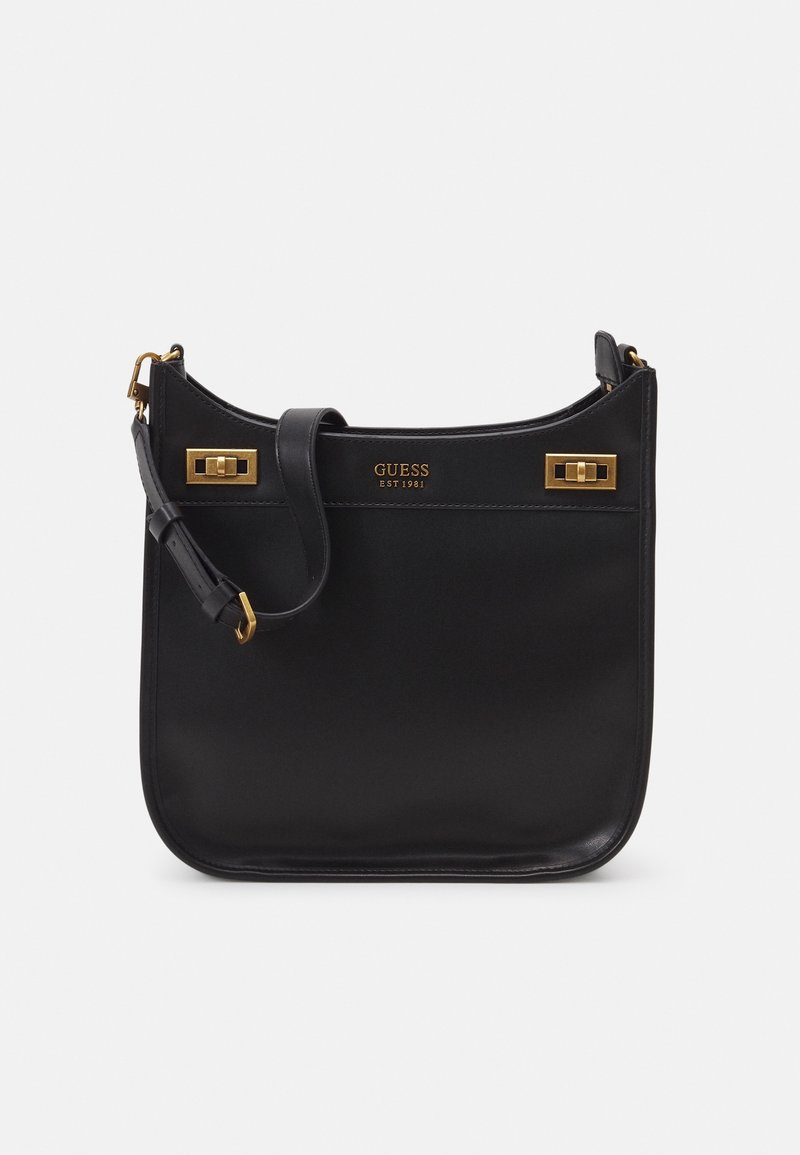 Sac à bandoulière en cuir noir GUESS avec quincaillerie dorée, bandoulière réglable et "GUESS EST 1981" embossé sur le devant.