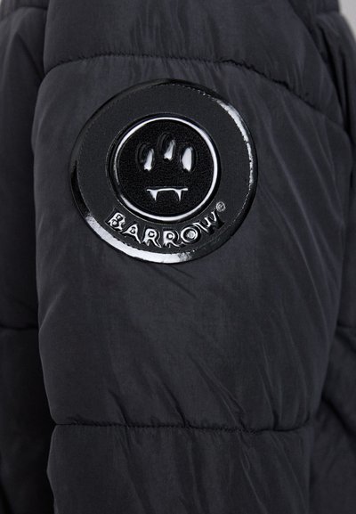 Black padded jacket with a glossy round patch featuring a smiling face, three claws, and the text "BARROW®" at the cuff.