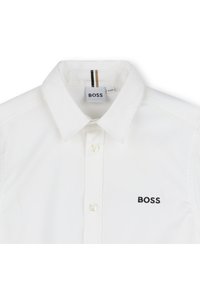 Witte button-up shirt met een kraag, voorzien van een zwart geborduurd "BOSS" logo op de linkerborst en subtiele gestreepte accenten in de kraag.