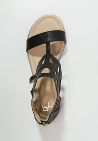 Svart läder sandalett med utskuren design, platt sula och dragkedjeslutning på baksidan. Tan-färgad innersula med synligt varumärke.