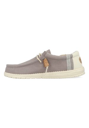 Scarpe slip-on in tela grigia con suola color crema, dotate di un'etichetta in sughero e dettaglio a righe sul tallone. Design semplice e casual.