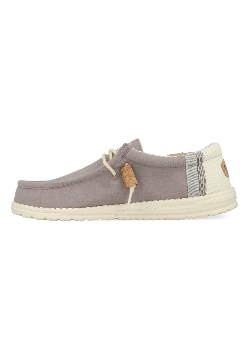 Scarpe slip-on in tela grigia con suola color crema, dotate di un'etichetta in sughero e dettaglio a righe sul tallone. Design semplice e casual.