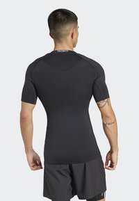 Zwarte korte mouwen compressie t-shirt met een strak ontwerp en naadloze constructie. Inclusief "TECHFIT" branding op de kraag.