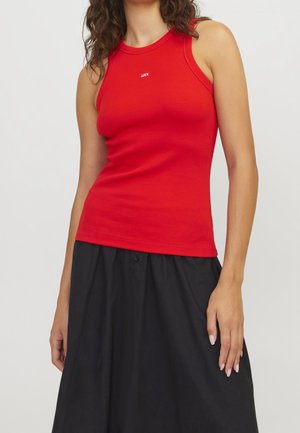 Red ribbed tank top with a round neckline and logo detail, paired with a black skirt. Features a fitted shape and soft texture.