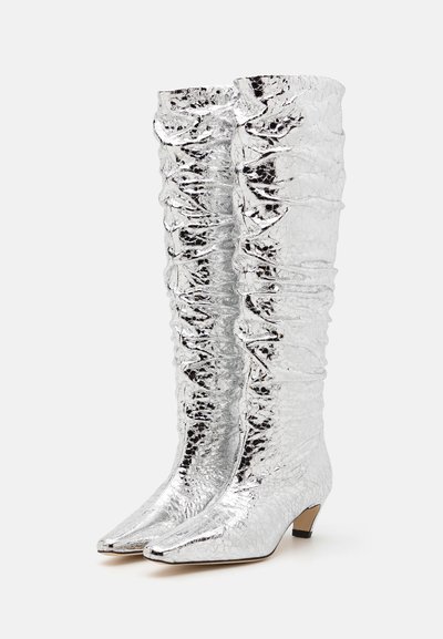 Silberne kniehohe Stiefel mit einer geriffelten Textur, spitzem Zehenbereich und einem kleinen Blockabsatz. Besitzt geraffte Details entlang des Schafts.