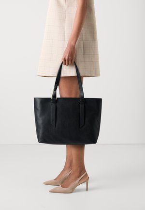 Black leather tote bag with textured finish, two sturdy handles, and open top design. Pairing with a light colored, check-patterned dress.