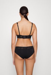 Black lace-trimmed bra and panties set. The bra features adjustable straps and a hook closure, while the panties have a smooth waistband.