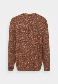 Brun stickad tröja med en fläckig textur, rund halsringning och ribbad fåll. Bakifrån syns en avslappnad passform och lätta sidoflikar.