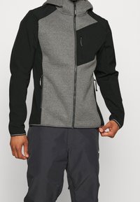 Gray and black zip-up jacket with a hood. Features textured fabric on the torso, smooth sleeves, and zippered pockets.