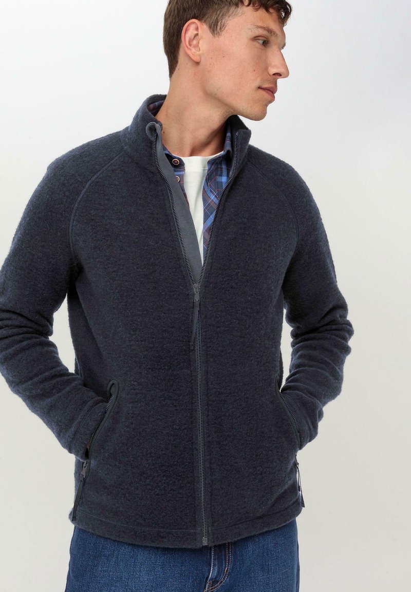 Fleece-Trainingsjacke in Dunkelblau mit hohem Kragen, Raglanärmeln, zwei seitlichen Taschen und strukturierter Oberfläche.