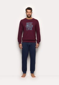 Maroon long-sleeve shirt with "BEST COACH EVER" text and a basketball graphic, paired with navy blue sweatpants. Soft fabric, relaxed fit.