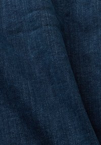 Tkanina dżinsowa w głębokim niebieskim kolorze o teksturowanym wykończeniu. Powierzchnia ma subtelny wzór skośny, pokazujący miękki, a zarazem trwały charakter.