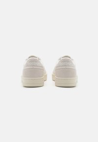 Vita mocka sneakers med en slät yta, rundade former och minimalisk design. Har präglad Reebok-logotyp på hälen.