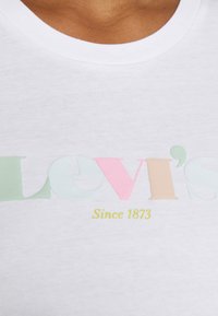 Valkoinen crew-neck t-paita, jossa on monivärinen "Levi's"-logo pastellisävyissä ja vihreä teksti, joka ilmoittaa "Since 1873". Pehmeä puuvillamateriaali.