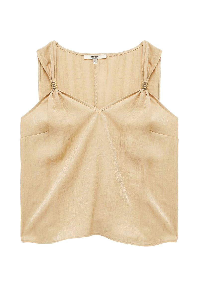 Beige ärmlös topp med strukturerad finish, med knytningar på axlarna och V-ringning. Inkluderar två framfickor.