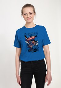 Camiseta de algodón azul con un gráfico de Capitán América en negro, rojo y blanco, con el texto "¡Un Nuevo Mundo Valiente!" y un diseño estilo cómic.