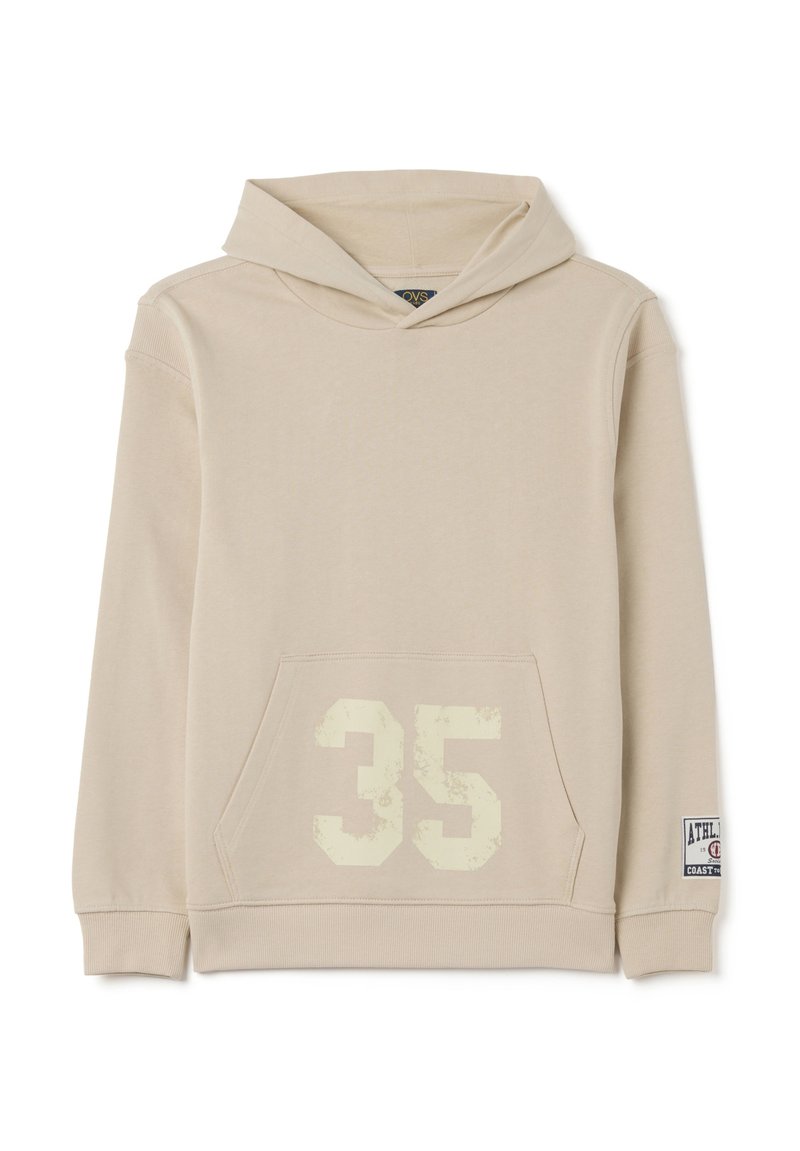 Sudadera beige hecha de una tela suave, con un bolsillo frontal, un "35" desvanecido en crema en la parte delantera y una etiqueta deportiva en la manga.