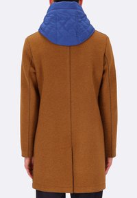 Cappotto di lana marrone con colletto trapuntato blu, caratterizzato da un design dritto, maniche lunghe e cuciture laterali. La texture appare liscia e calda.