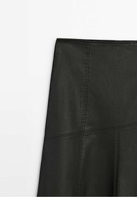 Gonna in pelle nera con vita aderente, texture liscia e dettagli delle cuciture visibili. Il design enfatizza una forma snella.