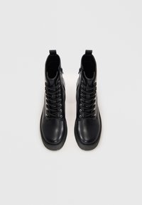 Μαύρες δερμάτινες μπότες μέχρι τον αστράγαλο με απαλή υφή, στρογγυλή μύτη, δέσιμο μπροστά, ασημένια κρίκους και παχιές ελαστικές σόλες.