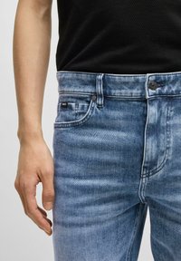 Vaaleansiniset farkut, joissa on slim fit -malli ja kulunut ilme. Farkuissa on perinteinen viisi taskua -design ja pieni merkkilogo sivussa.