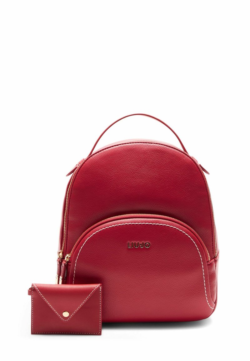 Sac à dos en cuir rouge avec poche avant zippée et petit portefeuille enveloppe assorti, tous deux avec surpiqûres blanches et détails dorés.