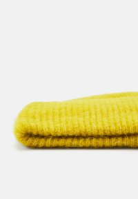 Geel gebreide stof, gevouwen, met een zachte, donzige textuur en een ribbelpatroon en losse garens, dat de heldere kleur benadrukt.
