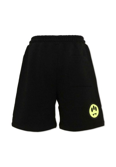 Shorts décontractés noirs avec taille élastique, poche arrière sur le côté droit, et un visage souriant néon jaune avec des crocs sur la jambe gauche.