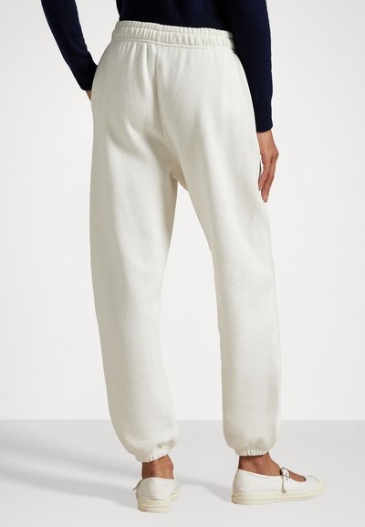 White, loose-fitting jogger pants made of soft fabric, featuring an elastic waistband, cuffed ankles, and side pockets.