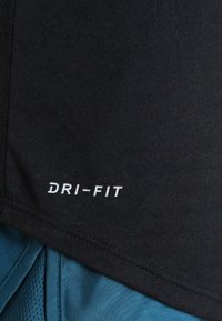 Tissu noir avec logo texte blanc "DRI-FIT" au-dessus d'un tissu de sport texturé bleu, mettant en avant des matériaux de vêtements de sport évacuant l'humidité.