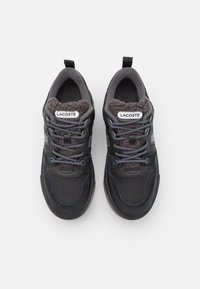 Czarne sneakersy z teksturowaną cholewką, puszystą szaro-skalową podszewką, szarymi sznurówkami i etykietą z logo na języku. Okrągły kształt noska i amortyzowana podeszwa.