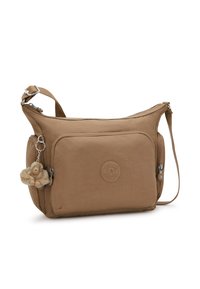 Borsa a tracolla marrone con tasca frontale con zip, tracolla regolabile, tasca laterale e un piccolo portachiavi a forma di scimmia di peluche attaccato al lato.