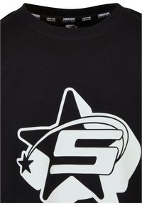 Sort bomulds t-shirt med et stort hvidt grafisk design af en stjerne og bogstavet "S". Rund hals, korte ærmer, glat tekstur.