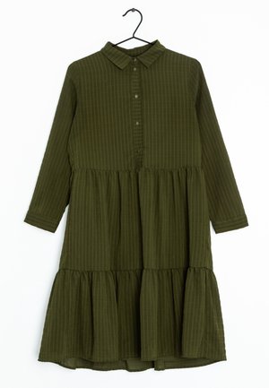 Długa sukienka z długim rękawem w oliwkowym kolorze, z falbanową spódnicą, zapinana na guziki z kołnierzem, wisząca na czarnym wieszaku.