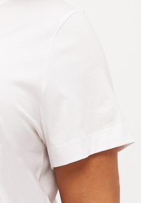 Weißes Baumwoll-T-Shirt mit Rundhalsausschnitt und kurzen Ärmeln, das eine glatte Textur und saubere Nähte aufweist.