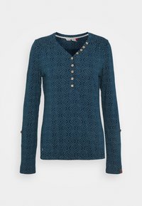 Námořnický modrý top s dlouhým rukávem, který má bílé puntíky, V-výstřih a dřevěné knoflíky, s knoflíkovými detaily na rukávech.